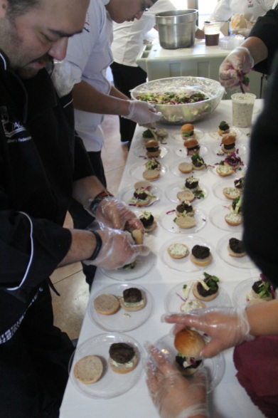 Instructor Brian Tatsukawa with students from Navajo Technical College assembling buffalo sliders with green chili and jalapeño mayo, kale slaw with a citrus vinaigrette, and a blue corn Rosemary bun (photo by Elizabeth Hoover).